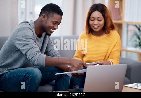 Maintenant, toutes nos factures sont à jour. Photo d'un couple qui passe par des documents tout en étant assis avec un ordinateur portable. Banque D'Images