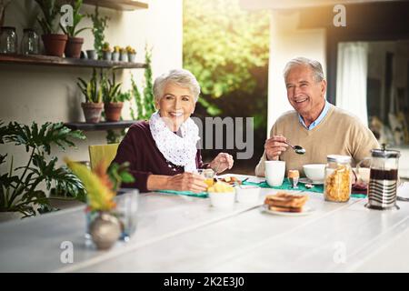 Les gens qui aiment le petit déjeuner sont toujours les meilleurs. Portrait d'un heureux couple senior prenant le petit déjeuner ensemble à la maison. Banque D'Images