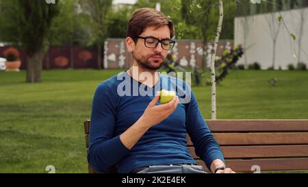 Employee Taking Break Work. Young man Eating a apple as snack. Enjoying an fruit. Banque D'Images