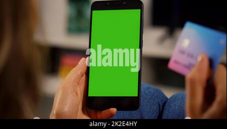 Woman Customer hands holding Credit Card and Smartphone with Chroma Key Green Screen. Close up view. Online Payment Concept. Shopping online. Stock Photo