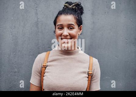 Vivre ma meilleure vie. Portrait rogné d'une jeune fille attrayante debout seule contre un mur gris dans la ville. Banque D'Images