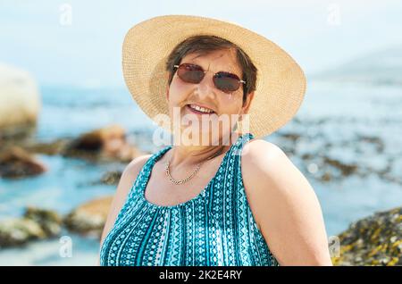 Il est temps de bronzer. Photo d'une femme mûre attrayante debout seule pendant une journée sur la plage. Banque D'Images