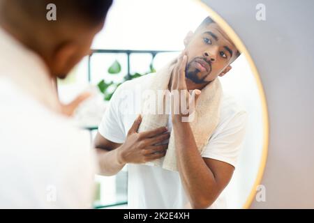 Cette nouvelle routine de soin de la peau a bien fonctionné pour moi. Photo d'un jeune homme concentré examinant son visage dans le miroir de la salle de bains. Banque D'Images