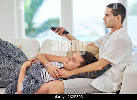 Qui se soucie de ce qui se fait quand nous nous sommes les uns les autres. Photo d'un couple gay regardant la télévision tout en se relaxant à la maison. Banque D'Images