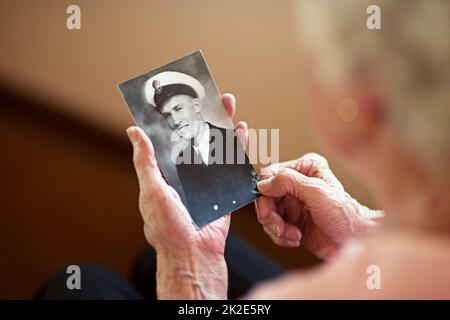 Il a vécu une vie d'honneur. Prise de vue rognée d'une femme âgée tenant une vieille photo noir et blanc d'un homme. Banque D'Images