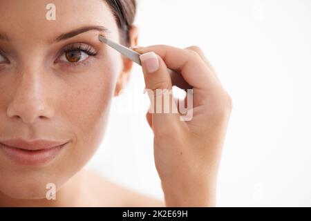 Elle tend ses sourcils. Portrait d'une jeune femme attirante qui plendit ses sourcils. Banque D'Images