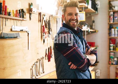 HES un artisan confiant. Portrait d'un beau jeune homme debout avec ses bras pliés dans un atelier. Banque D'Images