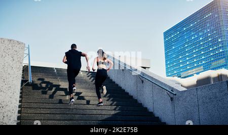 Faites ce qui fait circuler votre sang. Vue arrière d'un jeune homme et d'une jeune femme qui se rassemblent dans les escaliers de la ville. Banque D'Images