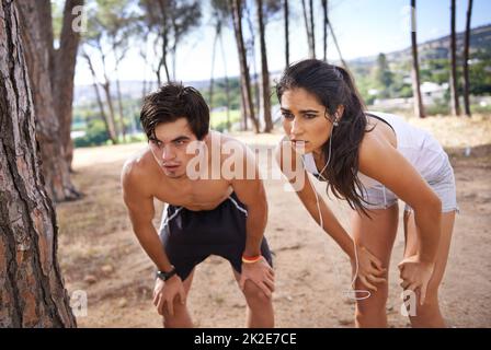 Prendre un reniflard. Photo d'un jeune couple en train de faire une pause après un exercice en plein air dans les bois. Banque D'Images