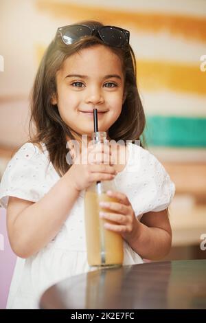 Si rafraîchissant. Prise de vue d'une adorable petite fille prenant une boisson froide dans un café. Banque D'Images