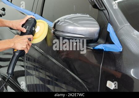 Homme travaillant pour le polissage, le revêtement des voitures. Le polissage de la voiture aidera à éliminer les contaminants sur la surface de la voiture.le cirage de la surface de la voiture causera le lustrage après le polissage de la voiture. Banque D'Images