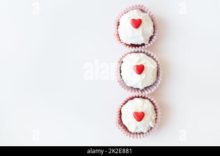 Saint-Valentin-14 février. Muffins au chocolat sucré avec crème au beurre et coeur rouge pour la décoration sur fond blanc. Banque D'Images