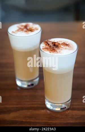 Deux verres de café latte arrosé de poudre de cacao. Banque D'Images