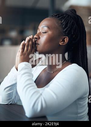 Je prie pour que les choses s'améliorent. Photo courte d'une jeune femme attirante s'agenouillant seule et priant dans sa maison. Banque D'Images