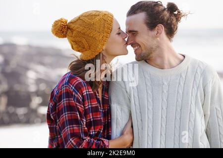 Baisers pour mon type préféré. Photo d'un jeune couple affectueux à la plage en hiver. Banque D'Images