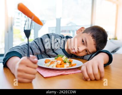 Je pense que j'ai perdu mon appétit maintenant. Prise de vue d'un jeune garçon malheureux refusant de manger ses légumes à la maison. Banque D'Images