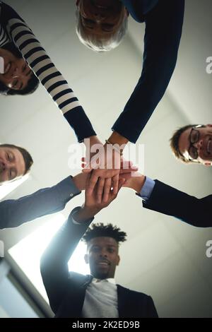 Ensemble, ils allaient directement au sommet. Photo sous angle d'un groupe de gens d'affaires qui se joignent aux mains lors d'un caucus. Banque D'Images