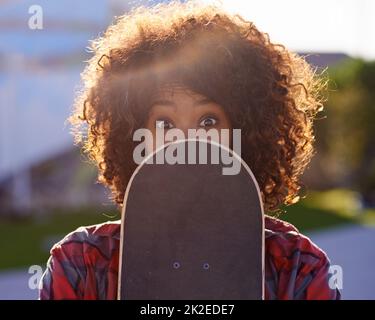 Un peu de plaisir dans le parc de skate. Une jeune femme avec une expression originale tenant son skateboard. Banque D'Images