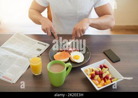 Commencez votre journée du bon pied. Petit plan d'une licence prenant le petit déjeuner à la maison. Banque D'Images