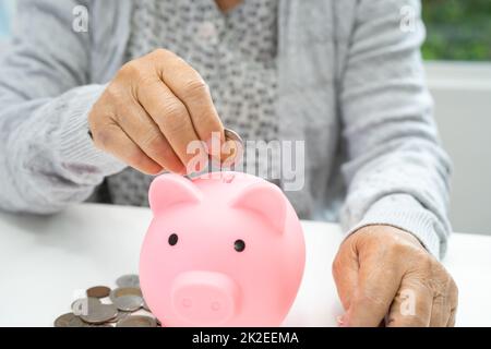 Femme asiatique âgée ou âgée tenant compte de l'argent de pièce dans la banque de piggy. Pauvreté, problème d'épargne à la retraite. Pauvreté, problème d'épargne à la retraite. Banque D'Images