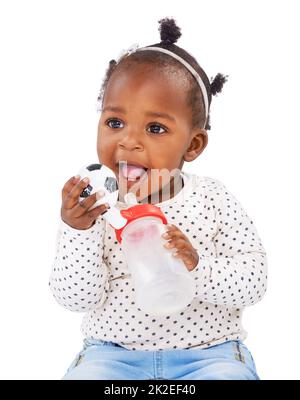 Shes heureux comme peut l'être. Studio photo d'une petite fille tenant une bouteille et un jouet. Banque D'Images