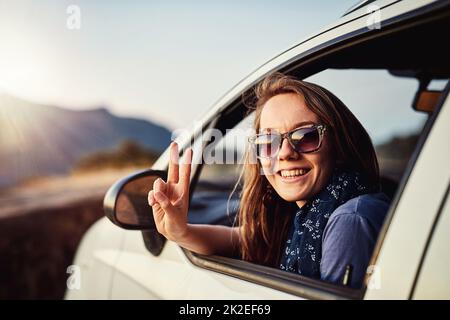 C'est facile. Portrait d'une jeune femme montrant une pièce d'affiche en étant assise dans sa voiture. Banque D'Images