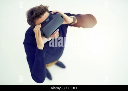 Découvrez plus que vous ne l'imaginez. Photo en grand angle d'un homme d'affaires portant un casque VR dans un bureau. Banque D'Images