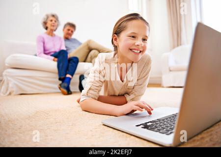 Elle se divertit partout. Photo de grands-parents regardant leur petite-fille à l'aide d'un ordinateur portable. Banque D'Images