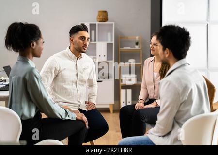 Deux personnes consolant le jeune homme pendant la thérapie de groupe Banque D'Images