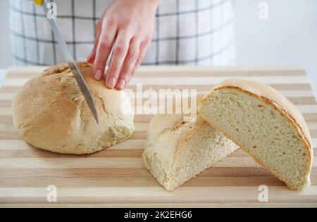 Femme coupant du pain maison sur une table en bois à la maison Banque D'Images