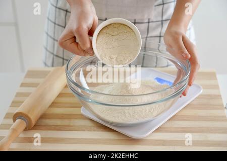 Une femme en gros plan pèse la farine sur la balance. Augmentation du prix du blé, de la farine et du pain. Préparation de pain maison. Crise économique. Banque D'Images