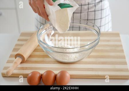 Gros plan de la main de femme versant la farine dans le bol. Augmentation du prix du blé, de la farine et du pain. Préparation de pain maison. Crise économique. Banque D'Images