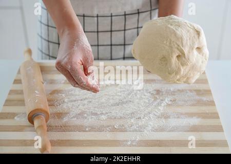 Femme met de la farine sur une table en bois et tient la pâte dans sa main. Augmentation du prix du blé, de la farine et du pain. Préparation de pain maison. Crise économique. Banque D'Images