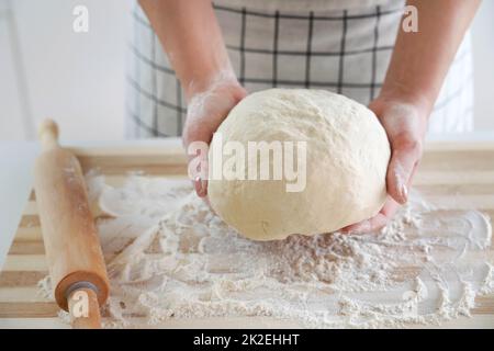 Une femme tient la pâte dans ses mains et montre à l'appareil photo. Augmentation du prix du blé, de la farine et du pain. Préparation de pain maison. Crise économique. Banque D'Images