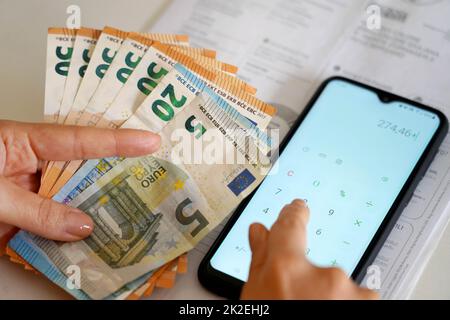 Hausse des prix des factures d'énergie pendant la crise financière. Main humaine comptant les dépenses facture d'électricité ou de gaz sur la calculatrice de smartphone. Banque D'Images