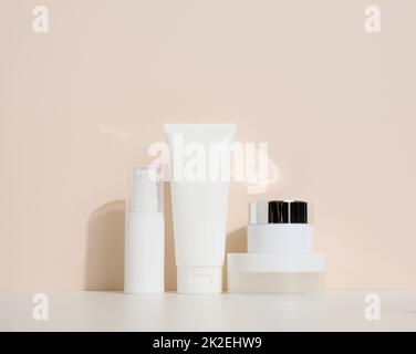 pot, bouteille et tubes en plastique blanc vides pour cosmétiques sur fond beige. Emballage pour crème, gel, sérum, publicité et promotion de produits, maquette Banque D'Images