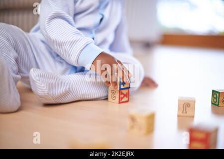 Jouets qui enseignent. Plan court d'un bébé garçon jouant avec des blocs de construction en bois sur le sol. Banque D'Images