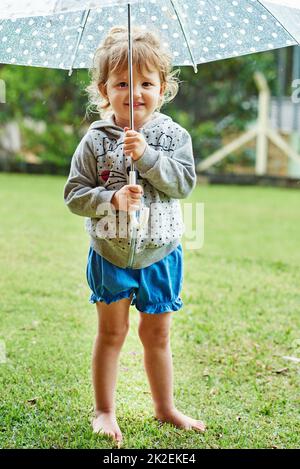 S'amuser sous la pluie. Portrait d'une petite fille gaie debout avec un parapluie à l'extérieur le jour des pluies. Banque D'Images