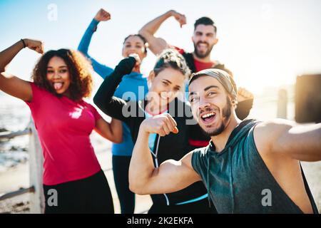 Notre travail acharné mérite un selfie. Plan court d'un groupe de remise en forme prenant un selfie pendant une course sur la promenade. Banque D'Images