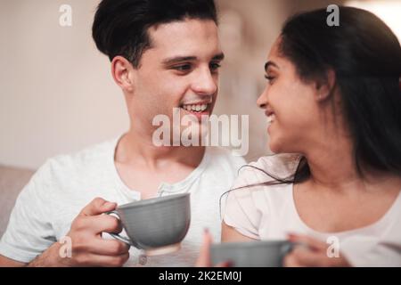 Le parfait début de journée. Petit cliché d'un jeune couple affectueux qui déguste son café du matin sur le canapé du salon. Banque D'Images