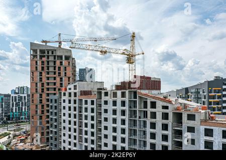 grues et bâtiments résidentiels en construction sur fond bleu ciel. site de construction de la ville. photo aérienne. Banque D'Images