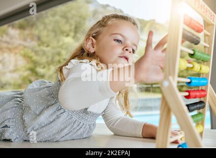 Education, learning and girl counting and practice math in homeschool activity. Child development, abacus and distance learning with child playing and Stock Photo