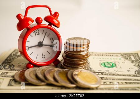 Alarm clock with coins on US dollar banknotes, finance installment loan time. Stock Photo