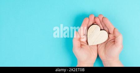 Femme tient un coeur dans sa main, fond coloré, espace de copie, symbole d'amour et de charité, concept d'espoir Banque D'Images