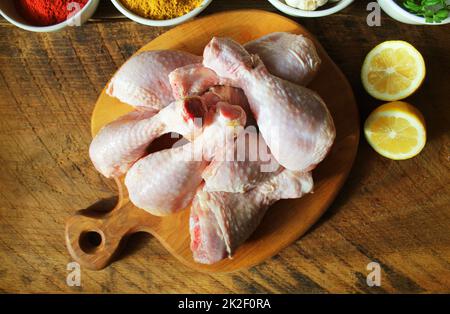 Cuisses de poulet non cuit brut, les pilons sur une planche à découper, la viande avec les ingrédients pour la cuisson Banque D'Images