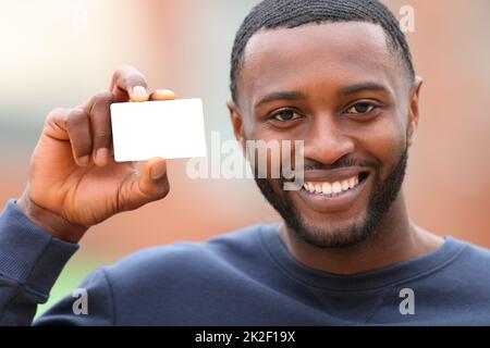 Un homme heureux avec une peau noire montrant une carte de crédit vierge Banque D'Images