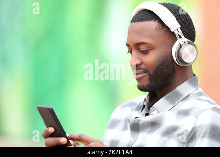 Homme à la peau noire écoutant de la musique vérifiant le téléphone portable Banque D'Images