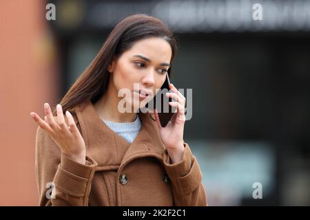 Une femme en colère dans la rue parle au téléphone Banque D'Images