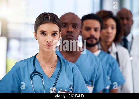 Ils sont les premiers dans le monde médical. Portrait d'un jeune groupe confiant de médecins debout les uns derrière les autres à l'intérieur d'un hôpital pendant la journée. Banque D'Images