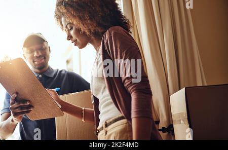 Tout ce dont j'ai besoin, c'est de votre signature. Photo courte d'une jeune femme attrayante signant pour une livraison à domicile. Banque D'Images